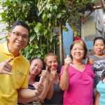 Anton Reyes posing and smiling with a group of happy residents in a neighborhood.
